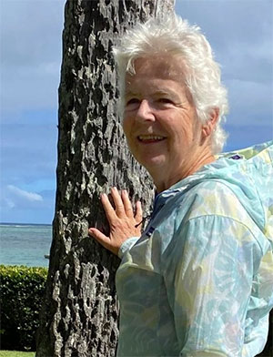 Lois Toyama reaches out to a tree at the beach